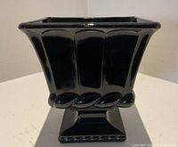 Front view of black glass vase showing flared square rim and paneled sides