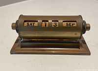 Front view showing Saturday 13 September on brass-tone rotary calendar
