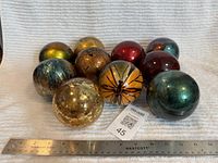 Group of ten metallic blown glass spheres with ruler showing scale