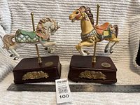 Two carousel horse music boxes side by side with ruler for scale