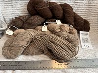 Four wool skeins on towel with ruler and MaxSold tag