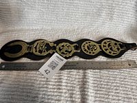 Full view of leather strap with five brass tacks next to ruler