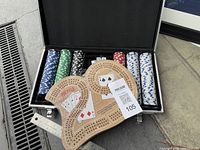 Open steel case showing poker chips, playing cards and cribbage board
