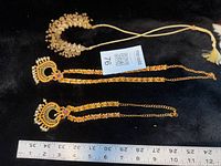 All three necklaces laid out with ruler for scale