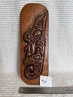 Full frontal view of carved plaque with ruler and note