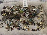 Full view of large pile of assorted earrings on towel