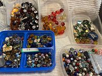 Overview of five tubs containing assorted beads of various colours, shapes and materials