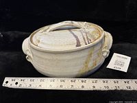 Side view of lidded stoneware bowl with ruler for scale