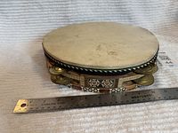 Tambourine side view showing skin head, frame thickness, brass jingles, ruler for scale