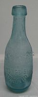 Front of aqua glass torpedo bottle showing “406 Yonge St Toronto” embossing