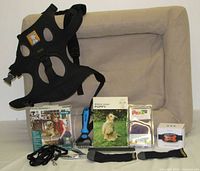 All items arranged including bed, harness, boxed collars, boots, leash, chain collar, grooming tool, booklet and sweater