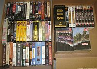 Two cartons filled with assorted VHS tapes showing Star Wars box set, Canada: A People’s History set and various movie titles