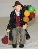 Front view of figurine showing seated man, balloons and red bag