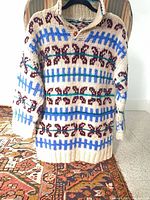 Full frontal view of cream wool Fair Isle sweater on hanger