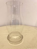 Full view of clear glass hurricane vase standing upright