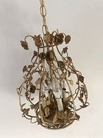 Full view of floral cage chandelier showing aged metal finish and chain