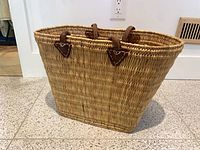 Side view of rectangular woven straw basket with leather handles