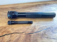 Large and small Maglite flashlights on wooden surface