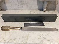Silverplate bridal cake knife with serrated blade and handle visible on marble surface