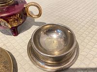 Silver-plated salt cellar beside porcelain oil lamp