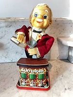 Front view of tin Smoking Bartender toy behind lithographed bar