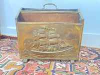 Full view of magazine holder showing brass front with ship scene