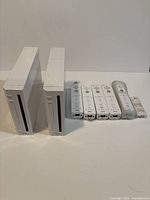 Two Nintendo Wii consoles and five Wii Remotes plus MotionPlus on white background