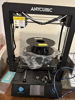 Front view of Anycubic Mega S printer with filament spool resting on heated bed