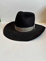 Side view of black felt hat showing rope hatband and brim