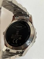 Back view showing Fossil branding, model numbers DW2A and FTW4038, stainless steel bracelet