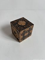 Cube form of wooden puzzle box showing decorative top and sides
