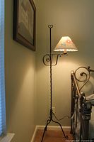 Entire floor lamp next to bed showing full height and shade illuminated
