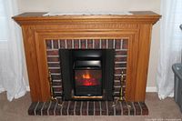 Full view of fireplace with insert, brass andirons, oak mantel, brick surround