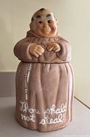 Full view of cookie jar with lid on showing figure and inscription