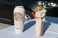 Vase and figurine side by side on table outdoors