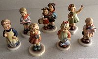 Seven Hummel figurines arranged on countertop