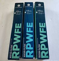 Front view of three boxed GE RPWFE filters upright