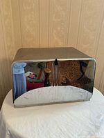 Front view showing mirrored chrome door with black pull and ribbed detail