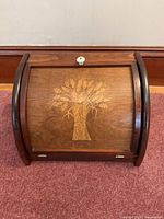 Front view of wooden bread box with wheat motif
