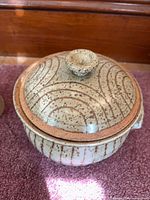 Lidded stoneware vessel showing speckled glaze and swirl motif