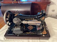 Left side view of Singer sewing machine showing external motor, handwheel, decals, wooden base