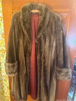 Front view of medium brown real fur long coat with burgundy lining