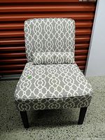 Front view of armless chair showing pattern, pillow and overall condition