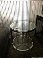 Front view of Elte round glass top side table showing chrome frame and stretcher