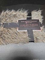 Front view of folded throw with Hotel Premier Collection Luxury Throw label and straps