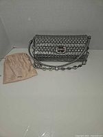 Full view of metallic silver Matelassé bag with strap and dust bag