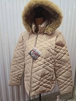 Front view of beige diamond-quilted puffer jacket on mannequin showing full shape and hood
