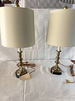 Two matching brass candlestick lamps with shades on table