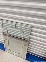 Full view of mirror leaning against wall showing rectangular shape, mirrored border, octagonal inset