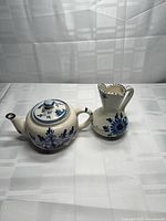 Teapot with lid and matching creamer side by side, showing blue floral decoration
